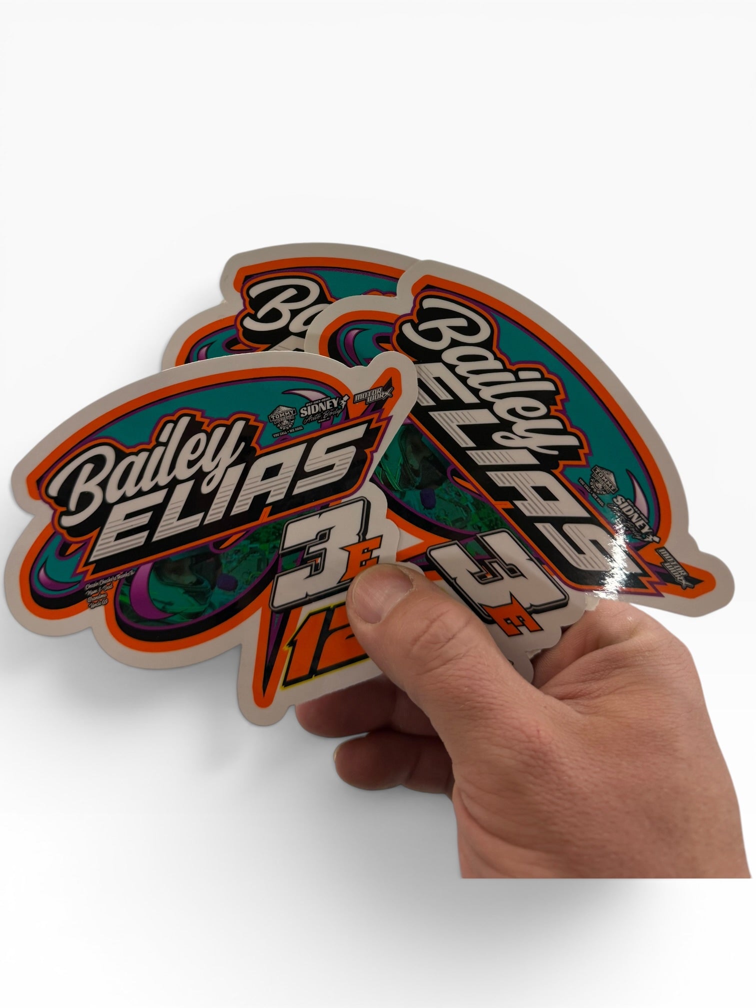 Hand holding a colorful 'Bailey Elias' sticker on a white background kart racing
